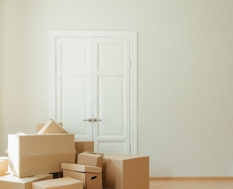 Person in Black Leather Boots Sitting on Brown Cardboard Boxes